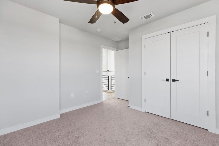 Unfurnished bedroom with light carpet, ceiling fan, and a closet