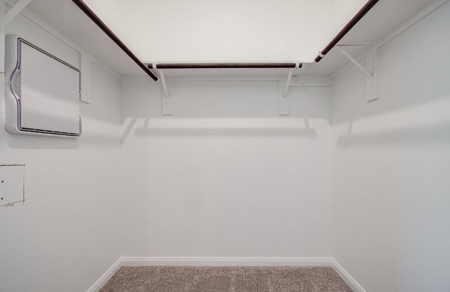 Spacious walk-in closet featuring dual hanging rods and plush carpeting, offering ample storage space.
