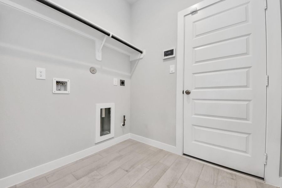 A perfect blend of functionality and comfort. Capture the essence of easy living with a first-floor laundry room, thoughtfully equipped with shelving for effortless organization. Both electric and gas connections available. Sample photo of completed home with similar floor plan. Actual colors and selections may vary.