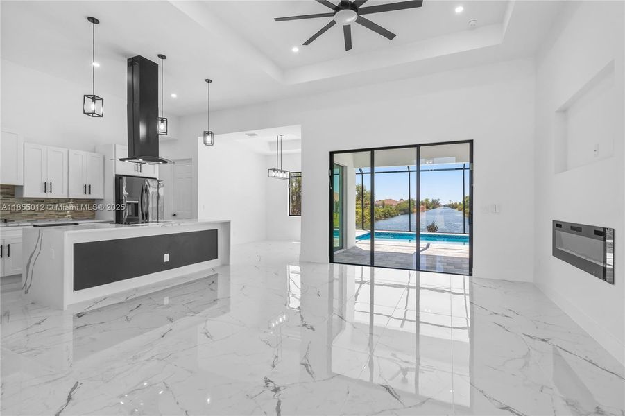 Kitchen with white cabinets, Stunning Quartz Counters, island exhaust hood. Tray ceiling, and stainless-steel refrigerator with ice and water dispenser