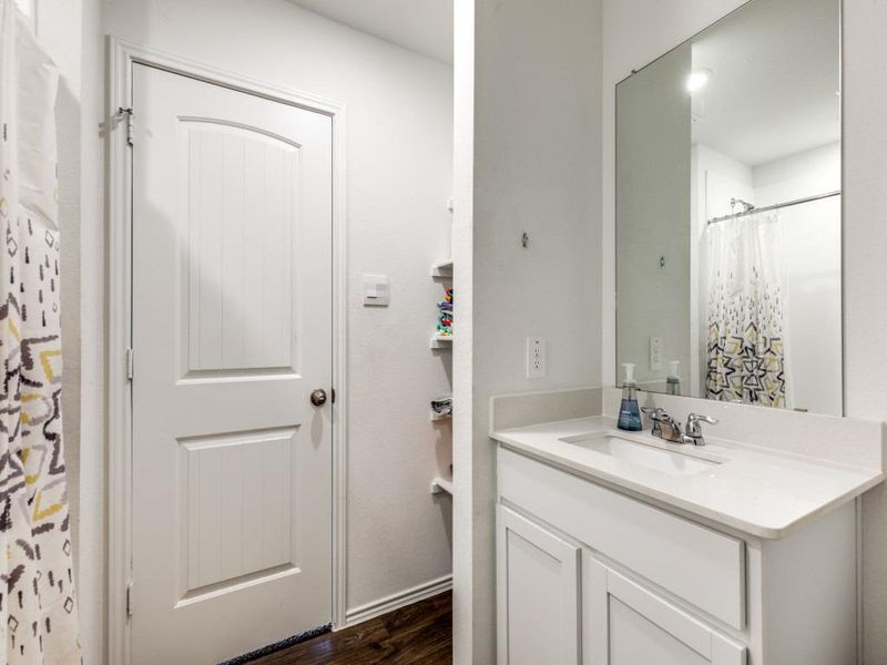 Full bath with dark wood-style flooring, vanity, and curtained shower