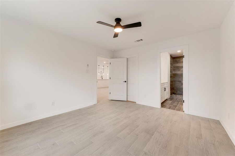 Unfurnished bedroom with ceiling fan, light wood-type flooring, and ensuite bath