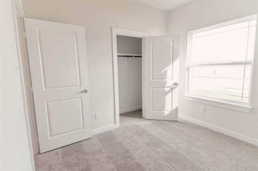 Unfurnished bedroom featuring light carpet and a closet