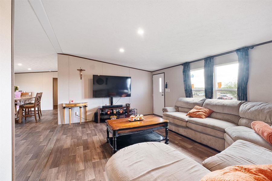 Living area featuring wood finished floors, vaulted ceiling, crown molding, and recessed lighting