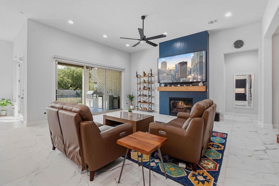 A spacious living area with white tiled floors, a warm fireplace, and access to a welcoming outdoor living space. A spacious living area with white tiled floors, a warm fireplace, and access to a welcoming outdoor living space.