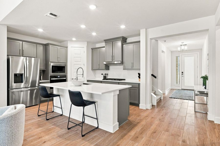 Gourmet kitchen and foyer view displaying 8-foot main floor interior doors, upgraded recessed lighting, and Level 6 tile flooring. Gourmet kitchen and foyer view displaying 8-foot main floor interior doors, upgraded recessed lighting, and Level 6 tile flooring.