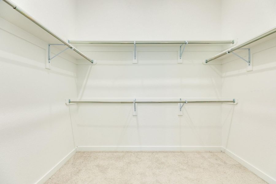 The primary walk-in closet is exceptionally spacious, featuring extensive shelving and multiple garment racks.