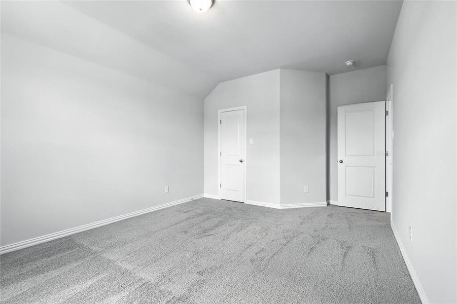 Unfurnished bedroom with carpet flooring and lofted ceiling