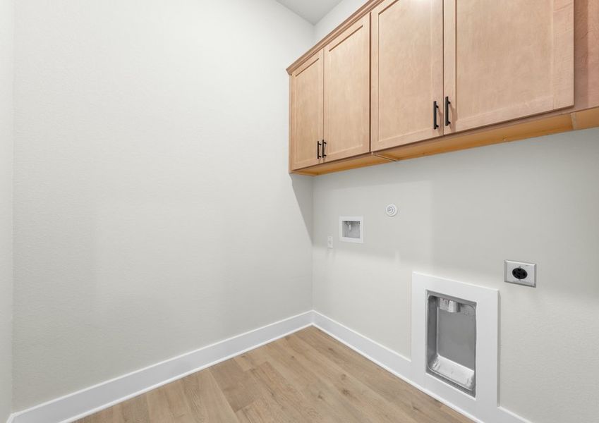 The laundry room has upper cabinetry for storage.