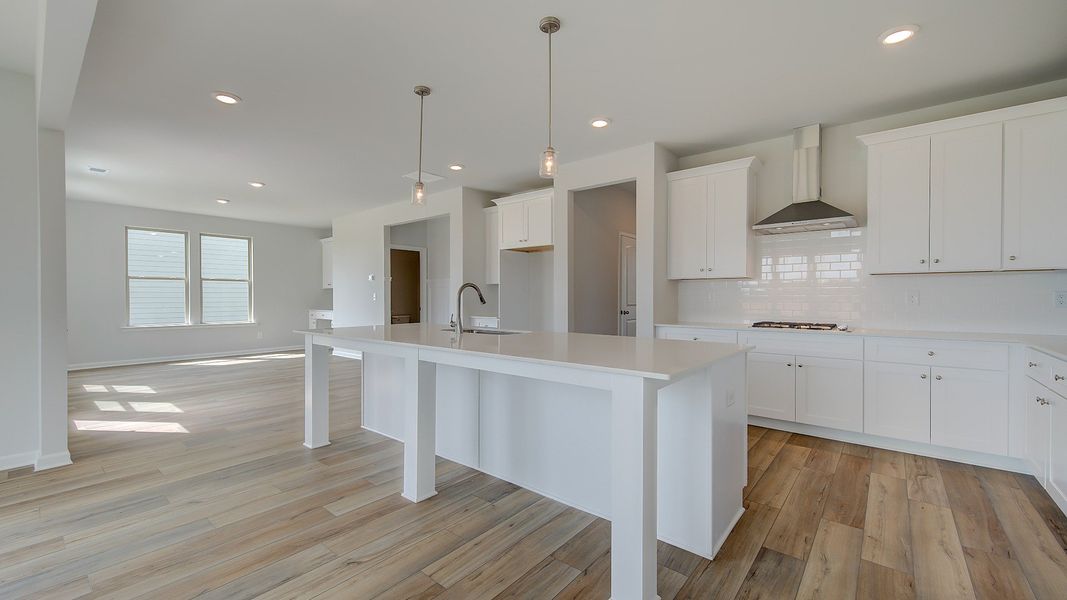 Stonefield kitchen with oversized island, neutral cabinetry, and tile backsplash at Brighton in Locust Grove, GA.