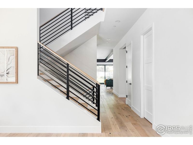 Tall ceilings featuring designer lighting rise over wide-plank white oak flooring and luxurious carpeting, while custom metal railings decorate the interior and exterior.