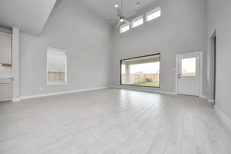 Welcome family and guests to your charming living room! With its high ceilings, recessed lighting, ceiling fan, custom paint, beautiful flooring, and large windows that let in abundant natural light, this room is perfect for gatherings. Sample photo of completed home with similar floor plan. Actual colors and selections may vary.