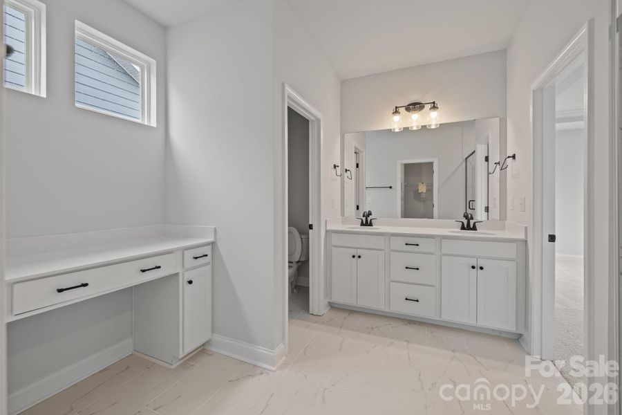 Primary bath with dual sinks, quartz countertops, additional vanity and tiled shower plus a large WIC!