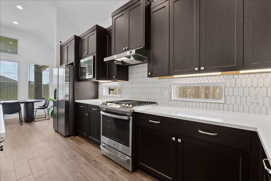 A gorgeous white diamond tile backsplash with contrasting black grout adds a modern, eye-catching design element, complemented by two charming peek-a-boo windows that bring in additional light and character. A gorgeous white diamond tile backsplash with contrasting black grout adds a modern, eye-catching design element, complemented by two charming peek-a-boo windows that bring in additional light and character.
