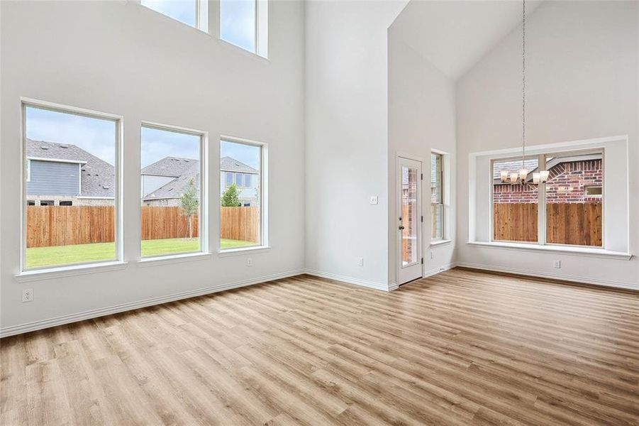 Unfurnished living room with a towering ceiling, a chandelier, and wood-type flooring