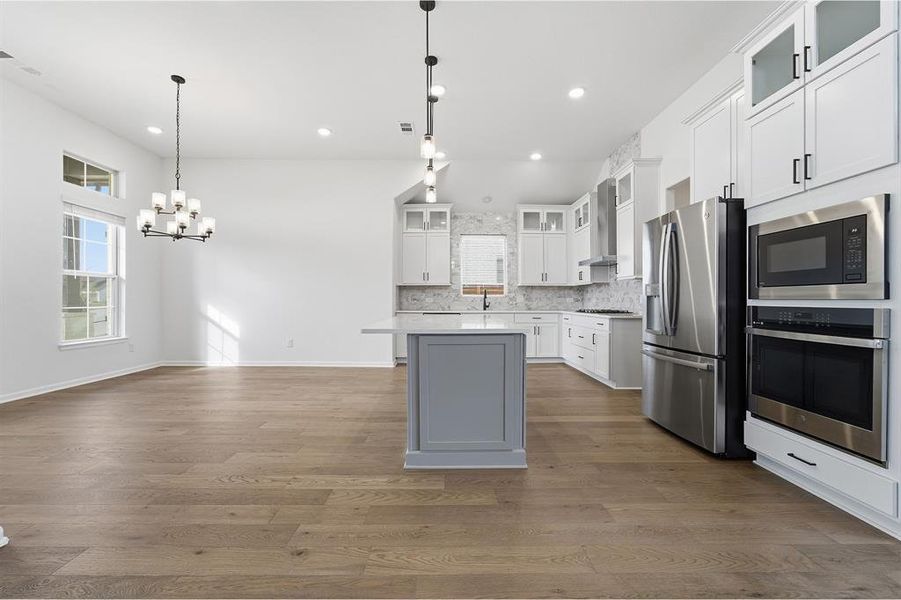 Open-concept kitchen and living area featuring wood-finish flooring, recessed lighting, and a chandelier