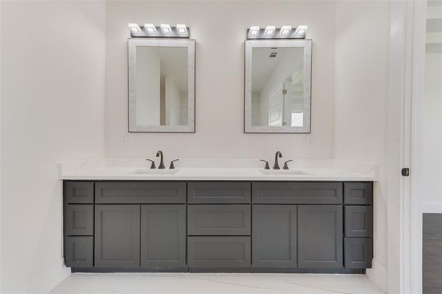 Dual vanity with dark shaker-style cabinetry, white countertops, and undermount sinks Dual vanity with dark shaker-style cabinetry, white countertops, and undermount sinks