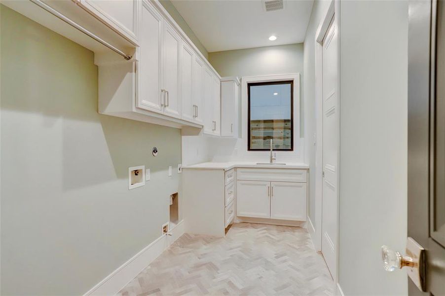 UTILITY ROOM:  Located on the first floor adjacent to the mudroom and access is the primary wardrobe. Note the Undermount stainless steel sink, polished steel rods, connections for both gas and electric dryer, and porcelain herringbone tile.