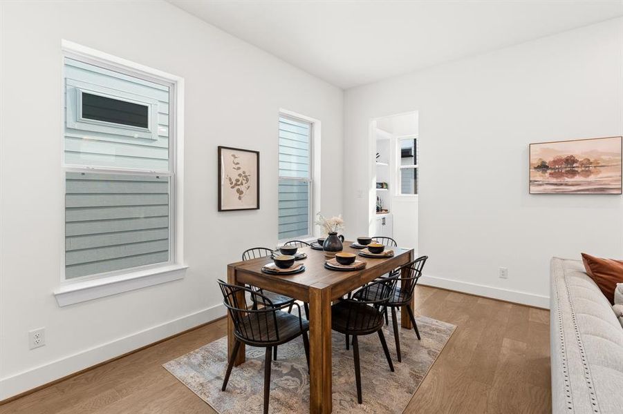 As you move further into the space, you will notice the dining area, which features a beautiful table and chairs that can comfortably seat six. The large windows in the dining area offer an abundance of natural light, creating a warm and inviting atmosphere as it reveals a hidden feature of the home.