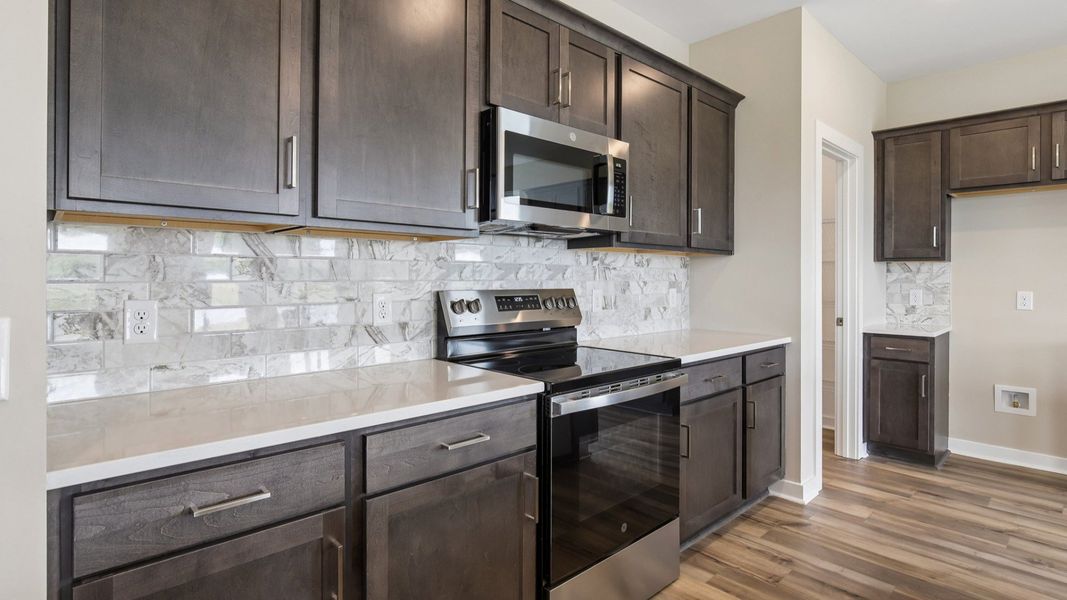 Kitchen with dark cabinetry, quartz countertops, and tile backsplash