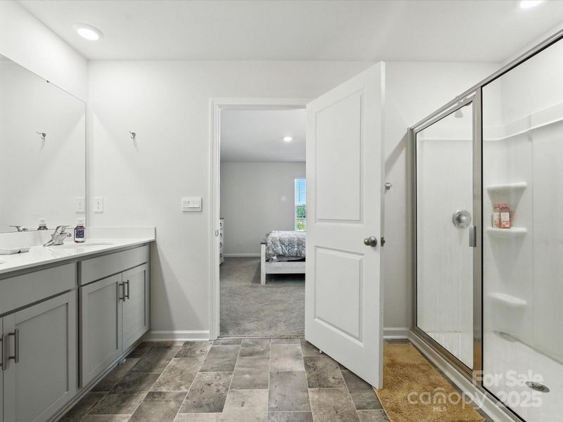 Primary bathroom showing convenient access to walk-in closet and bedroom. Tile flooring, dual vanities, and thoughtful layout create seamless flow in the primary suite.