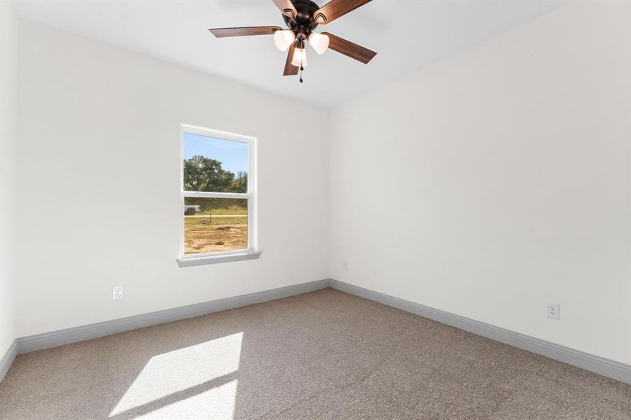 Carpeted empty room with baseboards and a ceiling fan