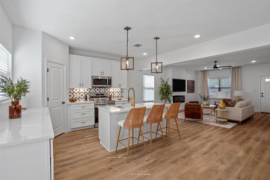 Kitchen featuring light hardwood / wood-style floors, white cabinetry, stainless steel appliances, and decorative light fixtures