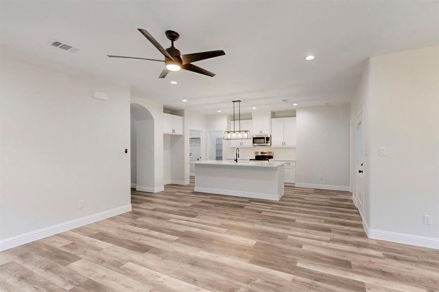 Unfurnished living room with sink, light hardwood / wood-style floors, and ceiling fan