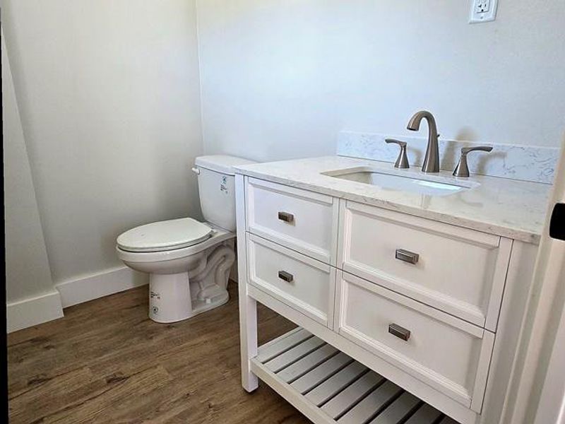 Half bath featuring vanity and dark wood-type flooring