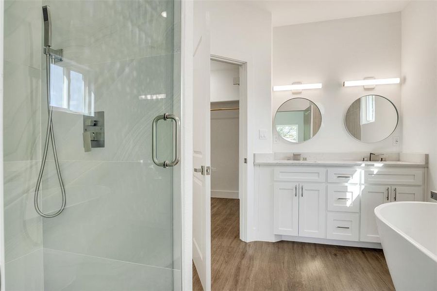 Full bathroom featuring a stall shower, light wood-style floors, double vanity, and a freestanding bath Full bathroom featuring a stall shower, light wood-style floors, double vanity, and a freestanding bath