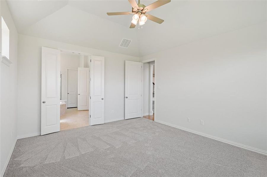 Unfurnished bedroom with ceiling fan, light colored carpet, and vaulted ceiling