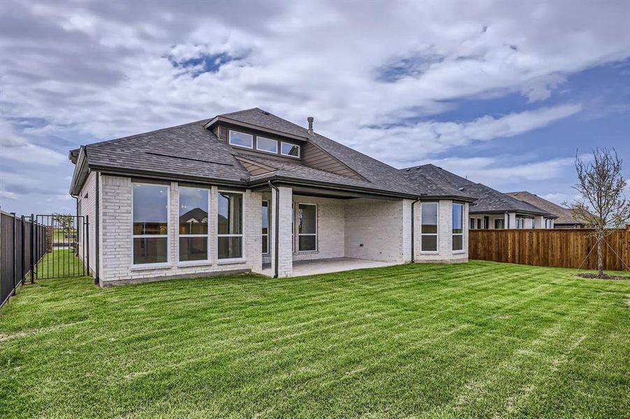 Rear view of house featuring a patio area, brick siding, and a shingled roof