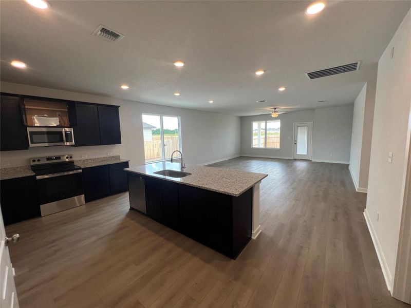 A well-appointed kitchen flows seamlessly into the open-concept living space, featuring a central island and recessed lighting.