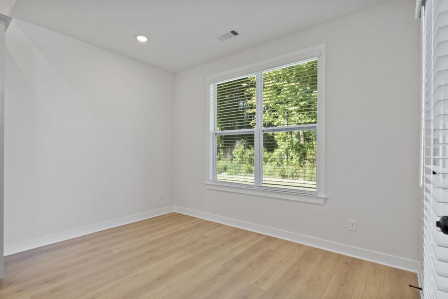 Bright room featuring wood-finish flooring, a large window with blinds, and recessed lighting