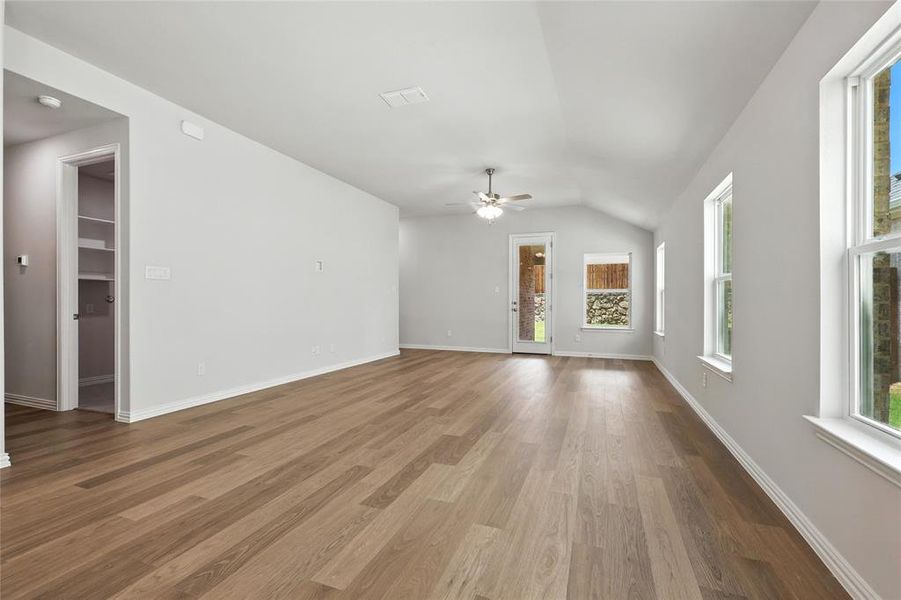 Unfurnished living room with dark wood-style flooring, vaulted ceiling, and ceiling fan