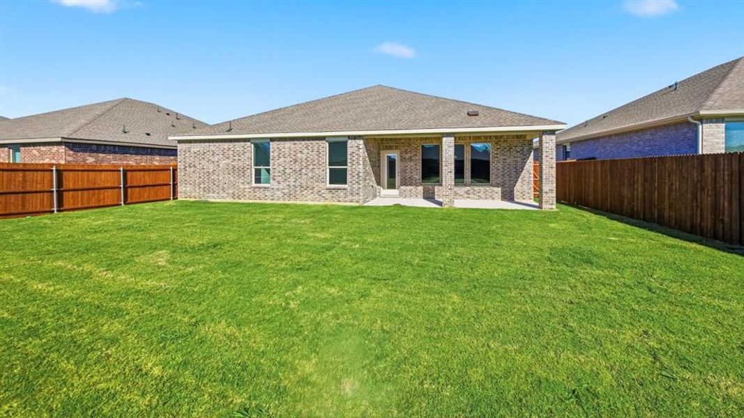 Rear view of house featuring brick siding, a fenced backyard, a patio, and a shingled roof