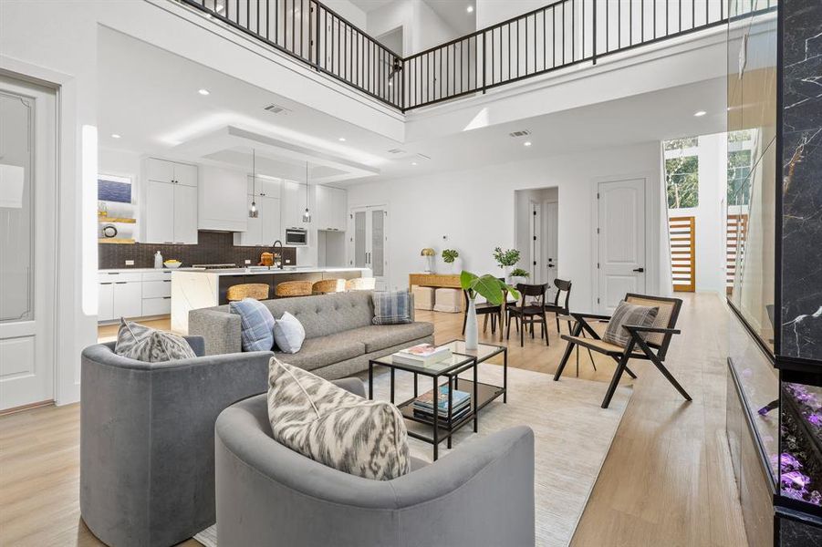 Living room featuring a towering ceiling, sink, and light wood-type flooring