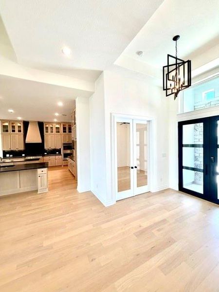 Elegant hardwood flooring extends throughout this luminous interior, featuring an inviting entrance with a modern chandelier. Elegant hardwood flooring extends throughout this luminous interior, featuring an inviting entrance with a modern chandelier.
