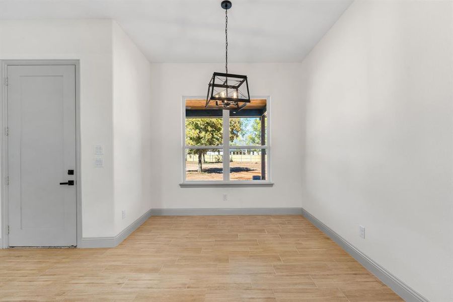 Unfurnished dining area with a chandelier and wood tiled floors