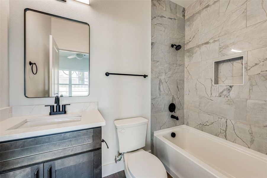 Full bathroom with oversized vanity, toilet, and tiled shower / bath combo