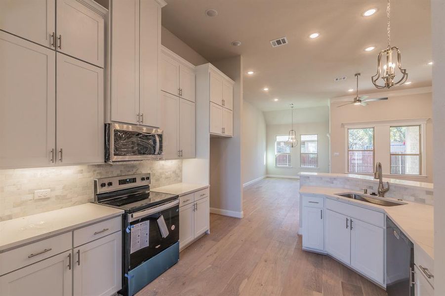 Kitchen with white cabinets, sink, ceiling fan, appliances with stainless steel finishes, and light hardwood / wood-style floors