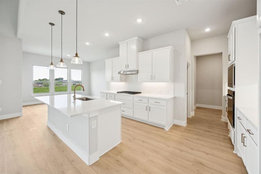 Kitchen with backsplash, a kitchen island with sink, decorative light fixtures, white cabinetry, and recessed lighting