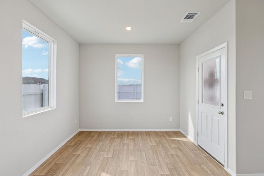 Image of a dining room with ligth grey walls, light brown wood-look flooring, a window and white trim Image of a dining room with ligth grey walls, light brown wood-look flooring, a window and white trim