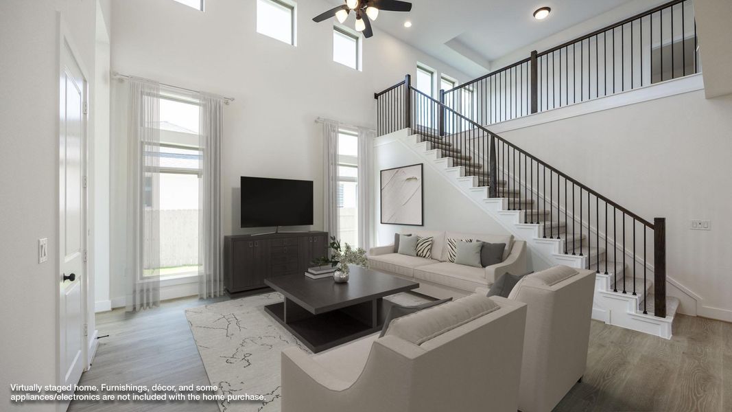 Living room with a high ceiling, wood finished floors, ceiling fan, and recessed lighting Living room with a high ceiling, wood finished floors, ceiling fan, and recessed lighting