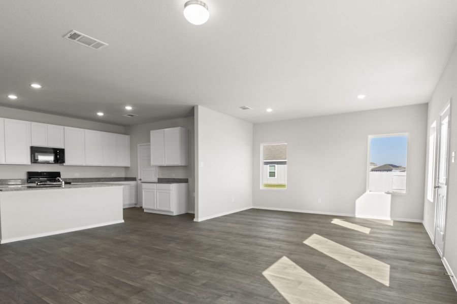 Image of a living room with light grey walls, dark brown walls, windows, white trim and an open kitchen to the left
