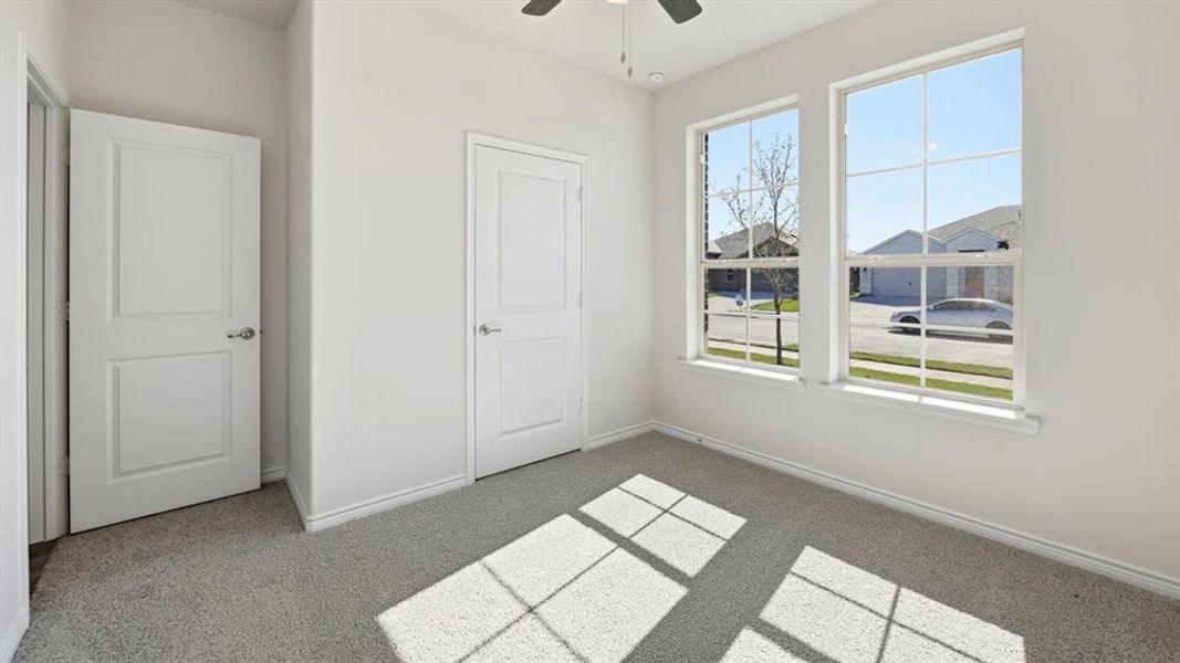 Unfurnished bedroom with light colored carpet and a ceiling fan Unfurnished bedroom with light colored carpet and a ceiling fan
