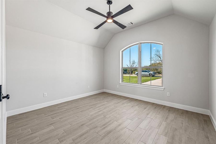 Spare room with lofted ceiling, wood finish floors, and a ceiling fan