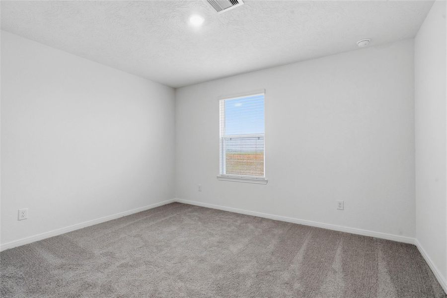 This secondary bedroom offers comfort and style with plush carpeting, neutral paint tones, recessed lighting, large window, and a generously sized closet.