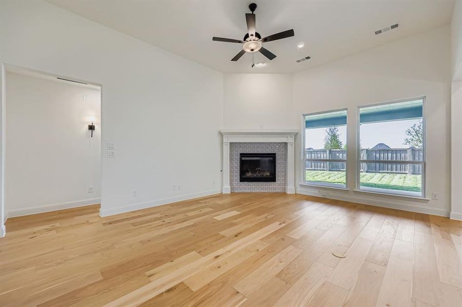 Unfurnished living room with light wood-style flooring, a glass covered fireplace, a ceiling fan, and recessed lighting
