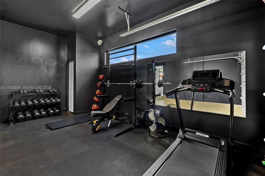 Interior space featuring dark-toned wall finishes, durable rubberized flooring, an expansive horizontal window, and a large wall-mounted mirror